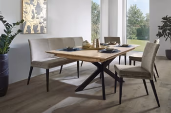 Auf dem Bild sehen Sie eine Eszimmergruppe mit einem Massivholztisch, einer Eckbank und drei Stühlen, die einen grauen Stoffbezug und schwarze Füße haben.